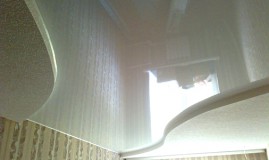 Двухуровневый потолок белый лаковый и бежевый тканевый в зале с центральной подсветкой